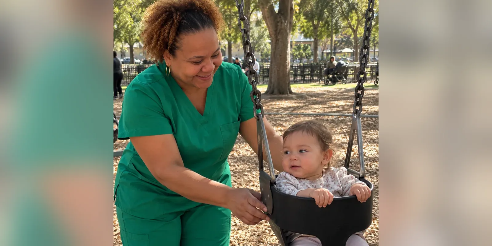 Arlene Excell pushing a smiling baby on a park swing