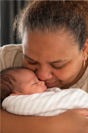 Arlene kissing a sleeping newborn's head